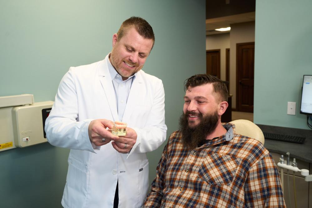 Dentist showing a teeth model for All-on-X Implant-Supported Dentures procedure