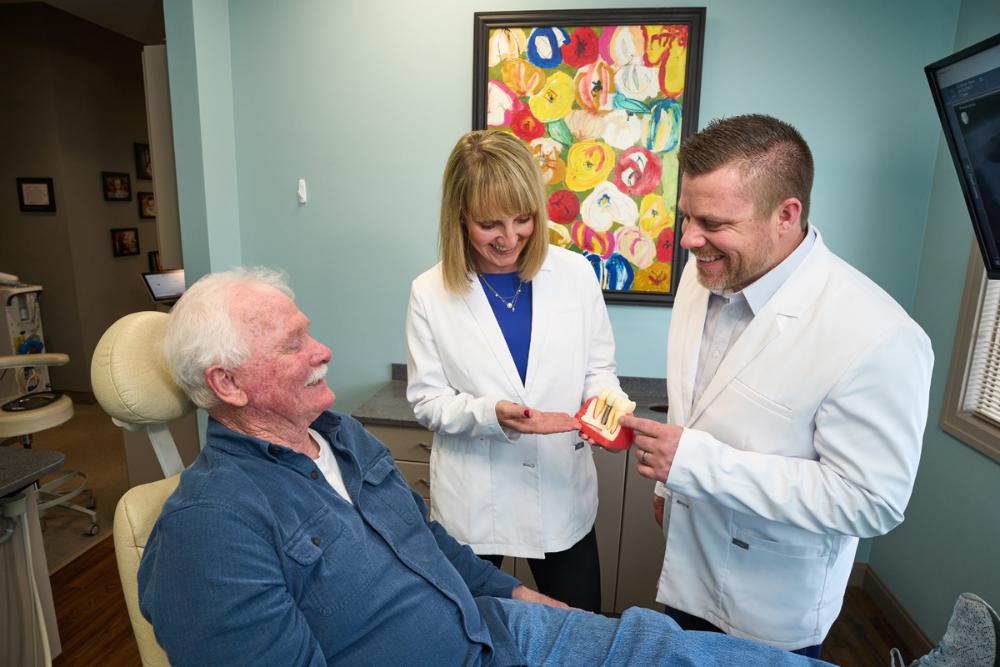 Dentists showing dental implant model