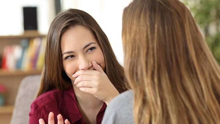 Woman talking while covering her mouth